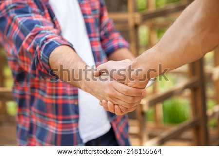 Cropped image of construction workers shaking hands in cabin at site