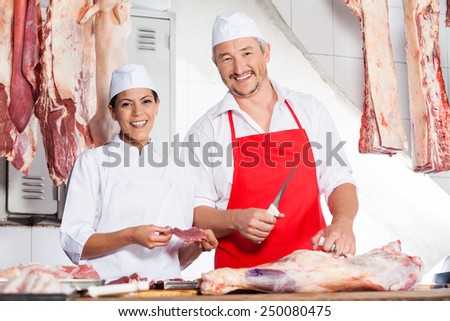 Portrait of confident male and female butchers working at counter in butchery