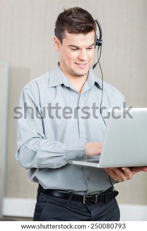 Smiling male customer service representative using laptop at office