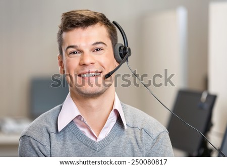 Portrait of confident male customer service representative wearing headset while smiling in office