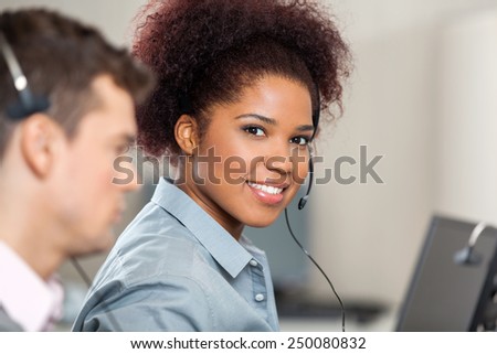 Portrait of young customer service representative with male colleague working in office