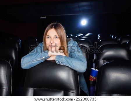 Mid adult woman leaning on seat while watching film at movie theater