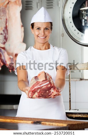 Portrait of confident female butcher offering fresh meat in butchery
