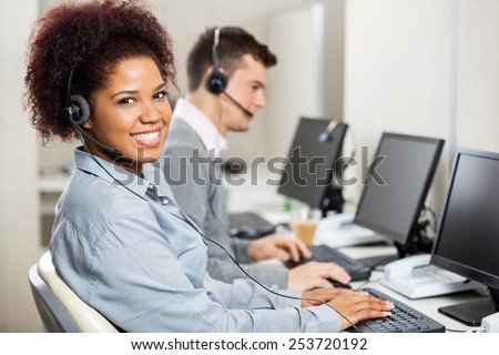 Portrait of smiling female customer service representative with male colleague working in office