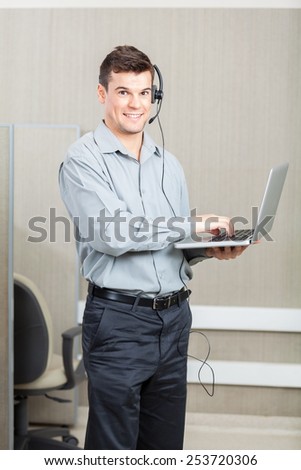 Portrait of smiling male customer service representative with laptop at office