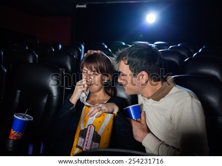 Man consoling woman crying while watching movie in cinema theater