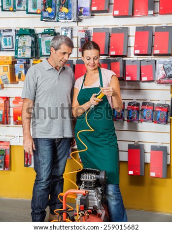 Saleswoman explaining air compressor to male customer in hardware store