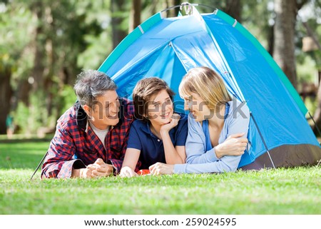 Smiling family camping in park on sunny day
