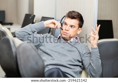 Angry customer service representative gesturing while using headset in office