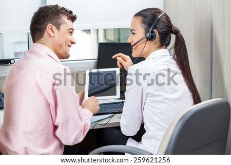 Happy call center representatives discussing while using tablet computer in office