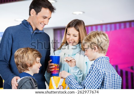 Happy family of four enjoying snacks at cinema