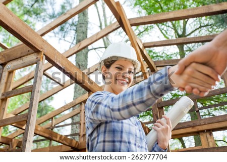 Portrait of smiling female architect greeting male colleague at construction site