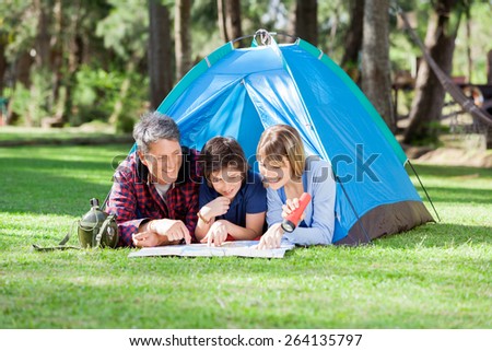Smiling family reading map at campsite in park