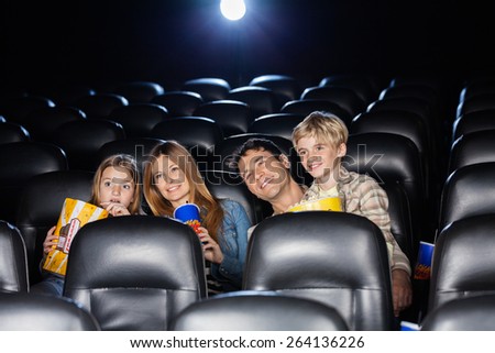 Smiling family of four watching film in movie theater