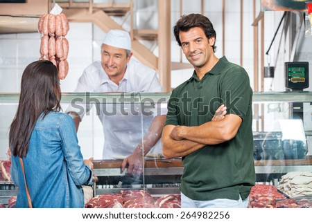 Portrait of happy mature man with woman buying meat at butchery