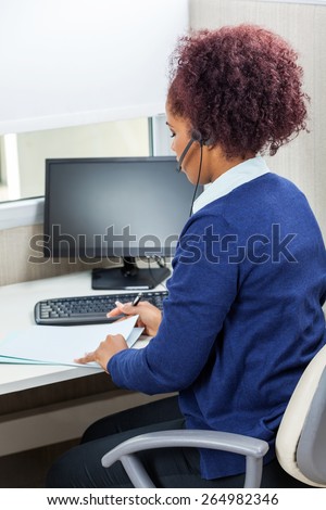 Side view of female customer service executive analyzing documents in office