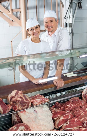 Portrait of confident butchers standing at meat counter in shop