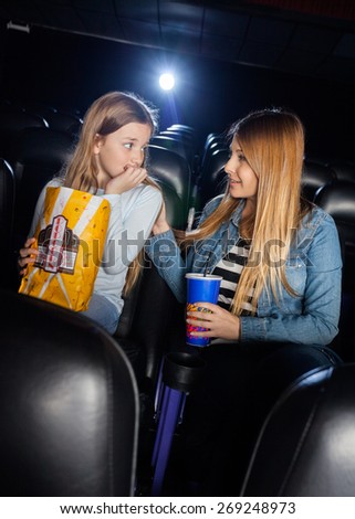 Mother consoling scared daughter while watching movie in cinema theater