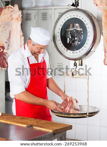 Male butcher weighing meat on scale at counter in butchery