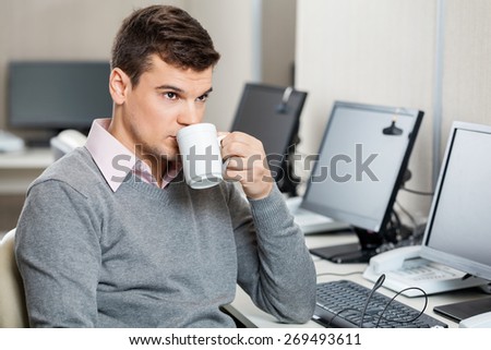 Young male customer service representative having coffee in office
