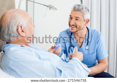 Happy male caretaker discussing prescription medicine with senior man in bedroom at nursing home