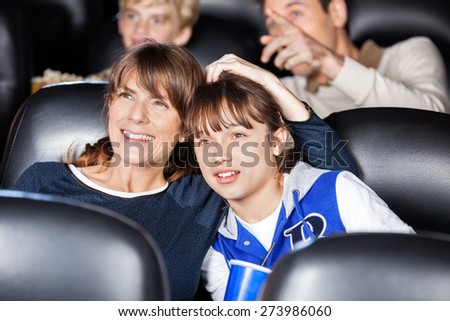Mother and daughter watching film with family in movie theater