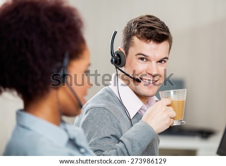 Portrait of smiling male customer service representative having tea in office