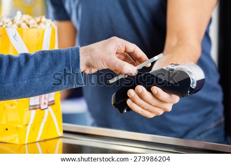 Cropped image of man making payment through smartphone using NFC technology at cinema