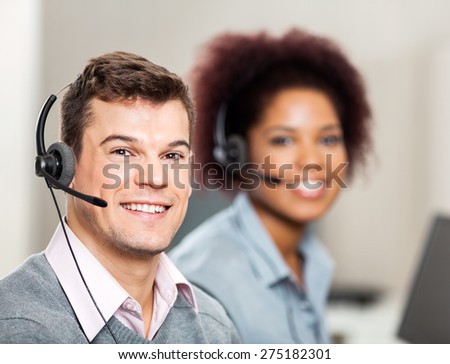 Portrait of smiling male customer service representative with female colleague working in office