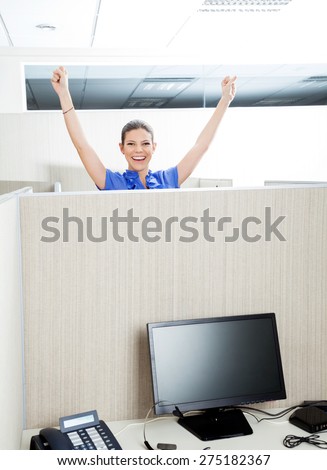 Portrait of female successful customer service representative with arms raised in cubicle