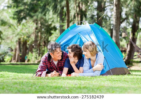 Happy family relaxing inside tent on camping holiday