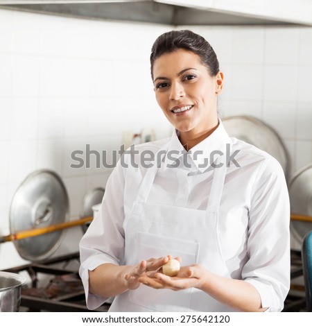 Portrait of smiling female chef holding pasta dough ball in commercial kitchen