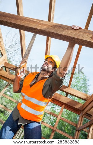 Low angle view of male construction worker cutting wood with handsaw at site