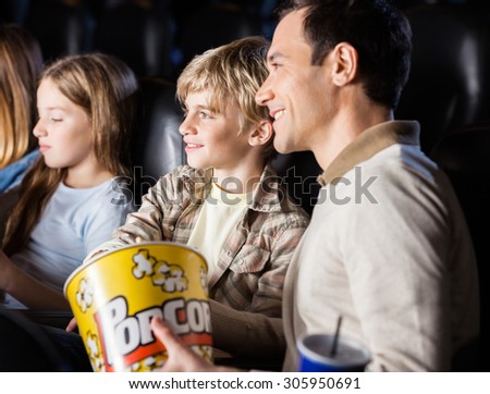 Family having popcorn while watching movie in cinema theater
