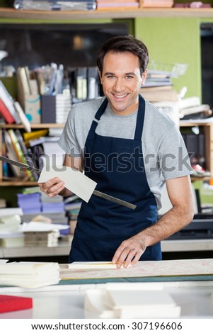 Portrait of smiling mid adult male worker working at table in paper industry
