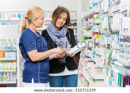 Mature chemist explaining product details to female customer in pharmacy