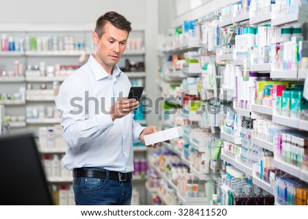 Mid adult male customer checking information on mobile phone while holding product in pharmacy