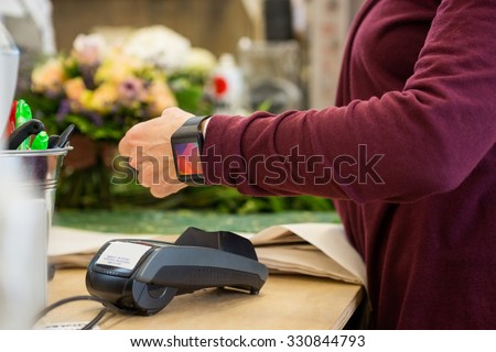 Cropped image of female customer paying through smart watch at flower shop