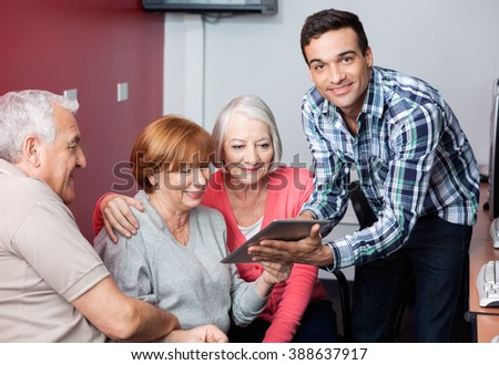 Tutor Guiding Senior Students To Use Digital Tablet In Classroom