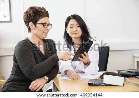 Patient Pointing At Digital Tablet Held By Doctor