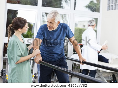 Patient Looking At Female Physiotherapist While Walking Between