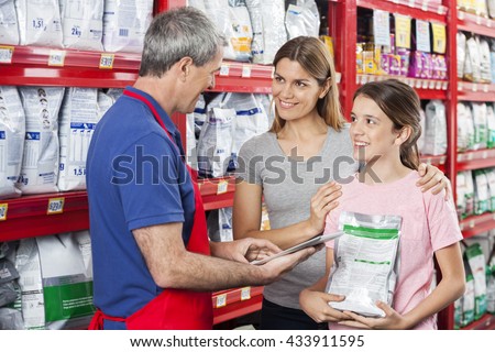 Family Looking At Salesman Using Digital Tablet In Pet Store