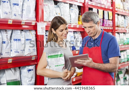 Woman Looking At Salesman Using Digital Tablet In Pet Store