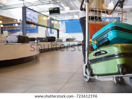Low Section Of Woman With Luggage In Trolley At Airport