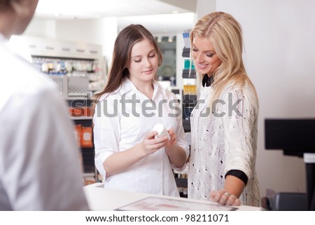 Female Pharmacist Advising Customer At Pharmacy at Cashier.
