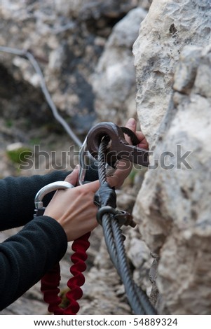 female hands caring for safety with a carabiner while climbing