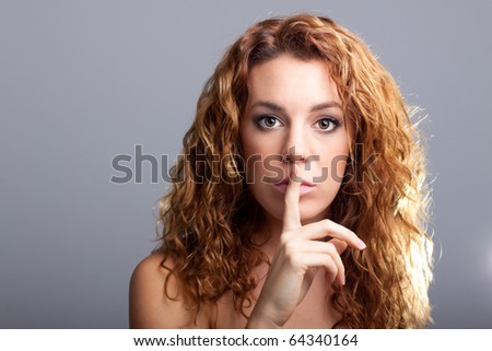 studio portrait of a beautiful redhead laying a finger on her mouth