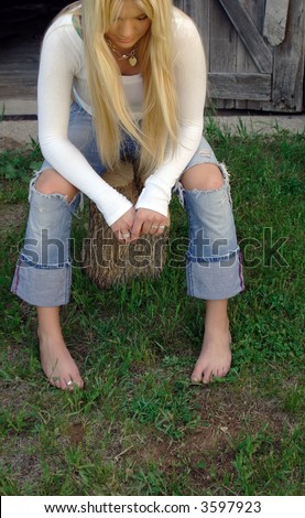 Young beautiful blonde woman in torn jeans looking down.