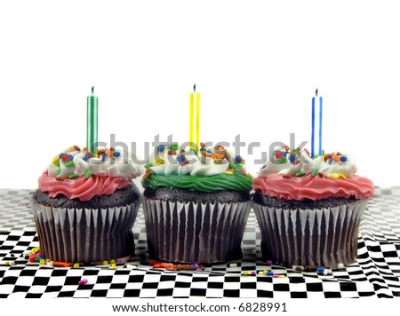 Three cupcakes with candles against a white background.