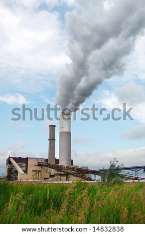 Smoke billowing out of the large smoke stack at a power plant.